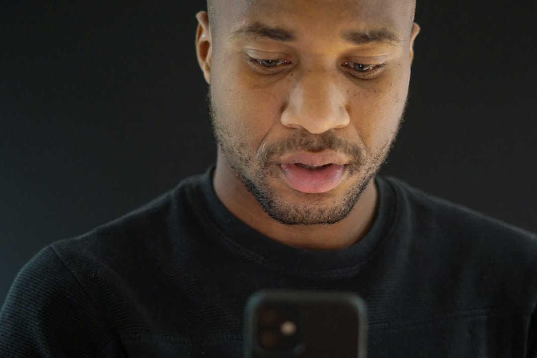 Un jeune homme seul, les yeux sur son téléphone